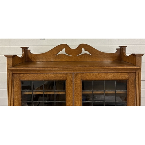 1479 - An early 20th century Art Deco light oak double bookcase with leaded glass doors and carved detail. ... 