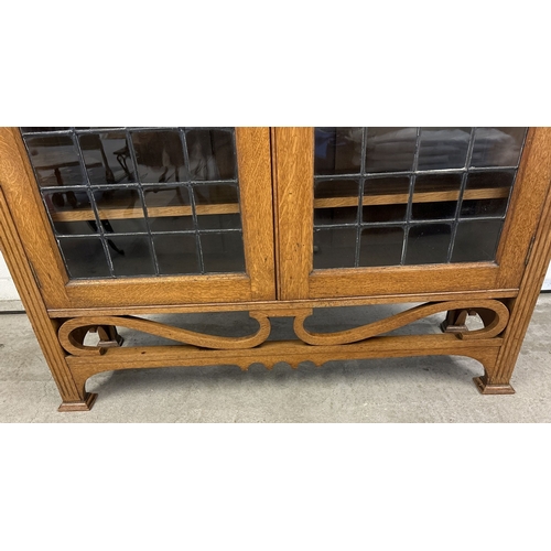 1479 - An early 20th century Art Deco light oak double bookcase with leaded glass doors and carved detail. ... 