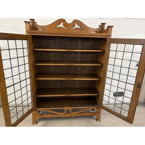 1479 - An early 20th century Art Deco light oak double bookcase with leaded glass doors and carved detail. ... 