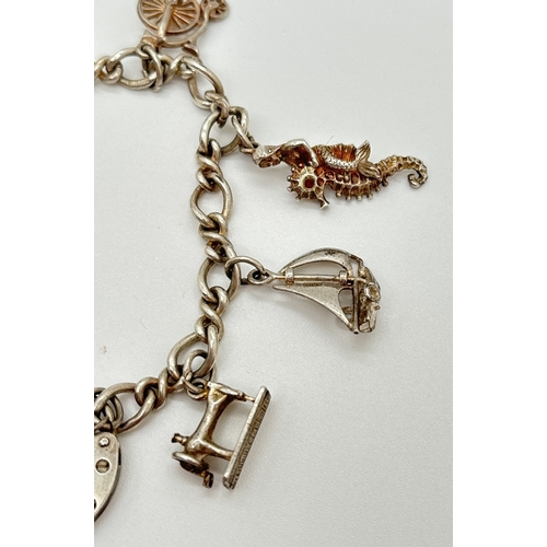 1105 - A vintage silver charm bracelet with 9 assorted silver & white metal charms and heart shaped padlock... 