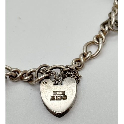 1105 - A vintage silver charm bracelet with 9 assorted silver & white metal charms and heart shaped padlock... 