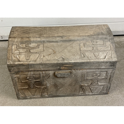 1492 - A wooden chest with shaped lid and carved Aztec figures throughout. Cut out handles to both sides an... 