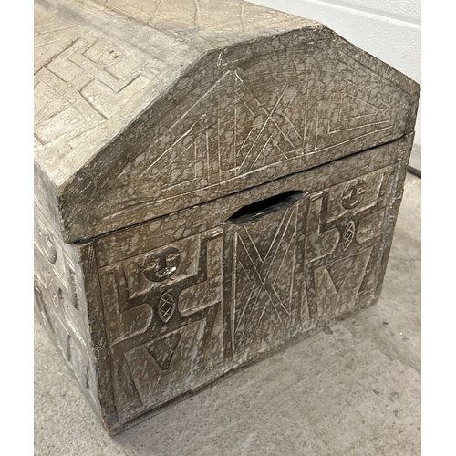 1492 - A wooden chest with shaped lid and carved Aztec figures throughout. Cut out handles to both sides an... 