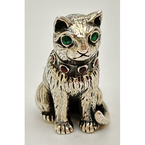1174 - A miniature silver pin cushion modelled as a cat, with a collar of small round cut garnets and set w... 
