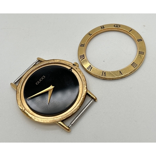 1136 - A Gucci watch in need of attention, without strap. Gold tone case with black face and gold tone hand... 