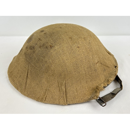 1214 - British WWI steel helmet complete with liner, rim, chinstrap and original burlap hessian cover. Fiel... 