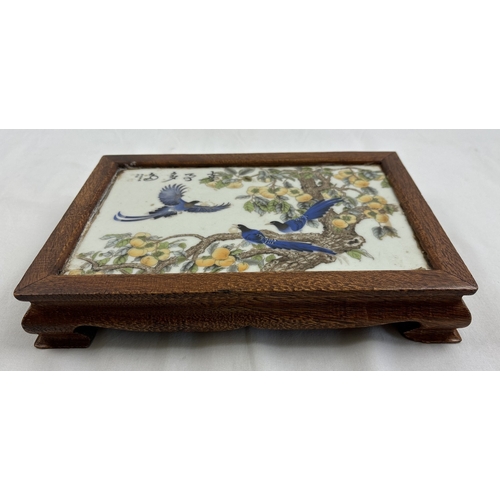 1290 - A Chinese porcelain and wood stand. Central ceramic tile depicting birds in a peach tree, with signa... 