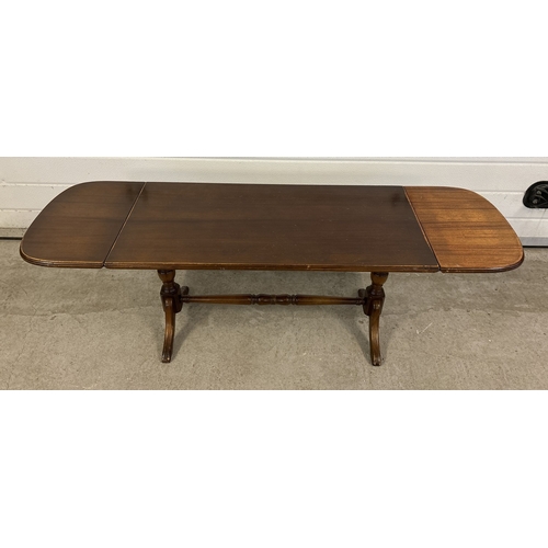 1489 - A vintage dark wood drop leaf coffee table with turned pedestal legs and stretcher. Sun fading to on... 