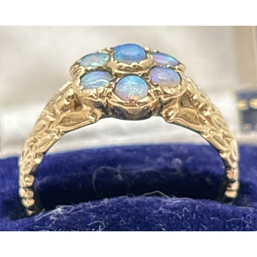 1008 - A vintage 9ct gold floral design ring set with 7 opal cabochons. Flower and leaf decoration to both ... 