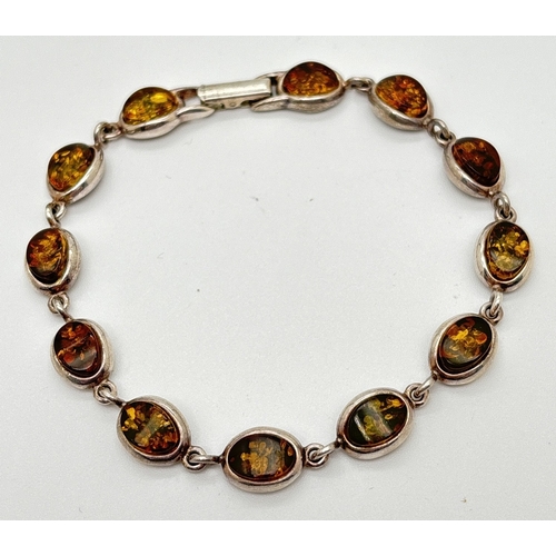 1013 - A silver and green amber bracelet with clip clasp. Each link an oval piece of amber in a silver beze... 