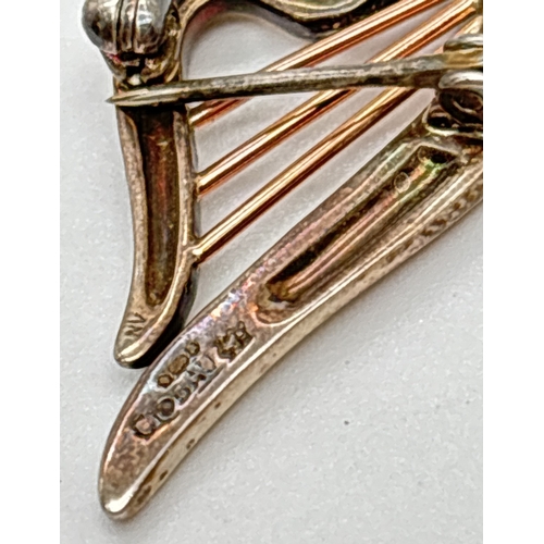 1041 - A small silver and Welsh rose gold harp shaped brooch by Clogau. Name and silver marks to back. Appr... 