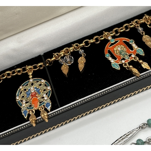 1045 - A boxed Brooks & Bentley costume jewellery dreamcatcher enamel and clear stone set bracelet together... 