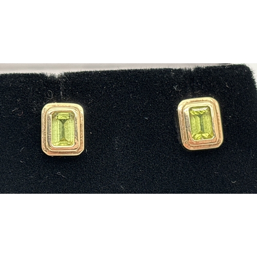 1061 - A pair of 9ct yellow gold square shaped stud earrings set with peridot stones. Earrings unmarked but... 