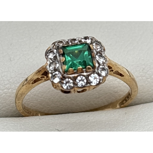 A 9ct gold created emerald and clear stone cluster style ring. Central square cut emerald surrounded by 12 round cut clear stones. Fully hallmarked inside band. Size M, Total weight approx. 1.6g.