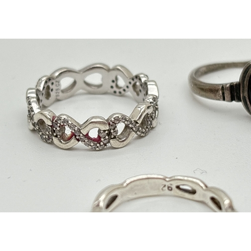 1078 - 6 silver modern design rings, mostly band style. To include infinity knot ring set with clear stones... 