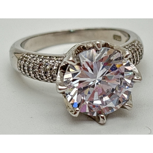 1083 - A 925 silver cocktail ring set with a large round cut clear stone with pave set pierced mount and sh... 