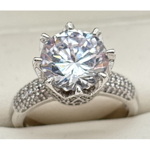 1083 - A 925 silver cocktail ring set with a large round cut clear stone with pave set pierced mount and sh... 