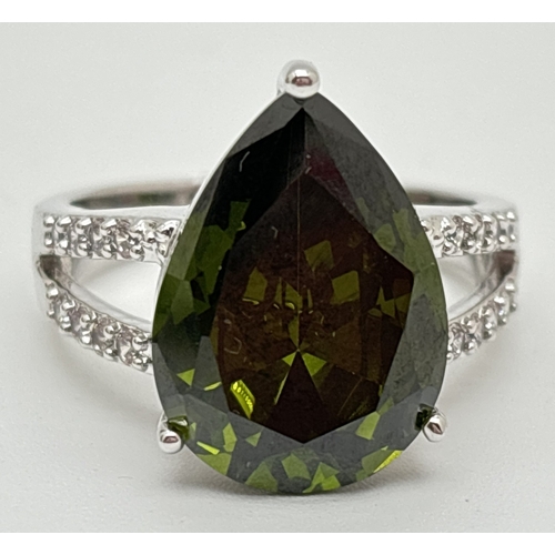 1095 - A Rhodium plated cocktail ring set with Swarovski crystals. A central single dark olive green pear c... 