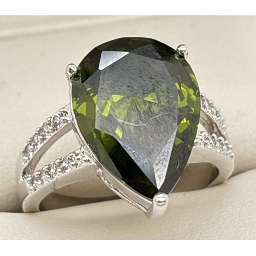 1095 - A Rhodium plated cocktail ring set with Swarovski crystals. A central single dark olive green pear c... 