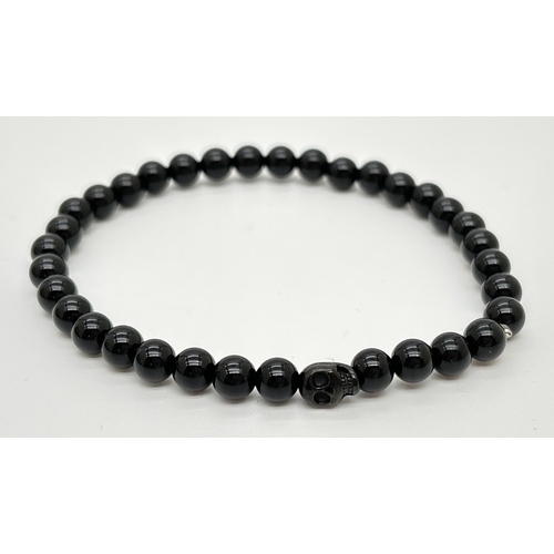 1103 - An unboxed black onyx men's bracelet by Simon Carter, London. Small round onyx beads with a single o... 