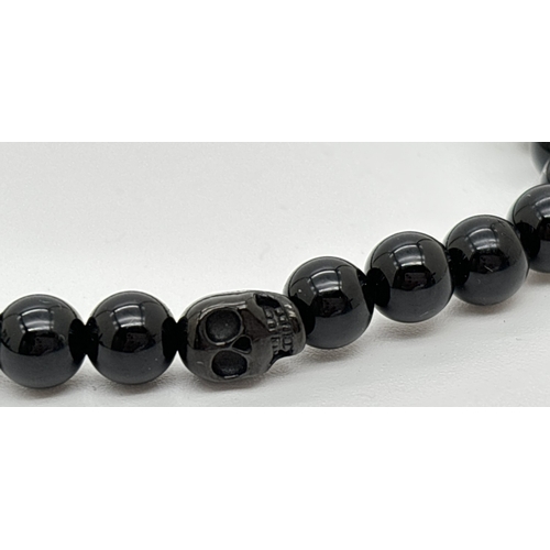 1103 - An unboxed black onyx men's bracelet by Simon Carter, London. Small round onyx beads with a single o... 