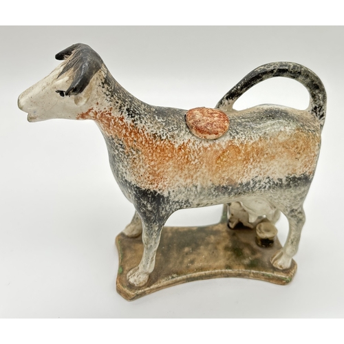 An Antique Pratt ware creamer in the shape of a cow being milked by a milkmaid. Complete with stopper. In a brown and black stippled decoration with green/brown glazed base. Approx. 13 x 15cm. Being sold on behalf of Animal Free Research UK.