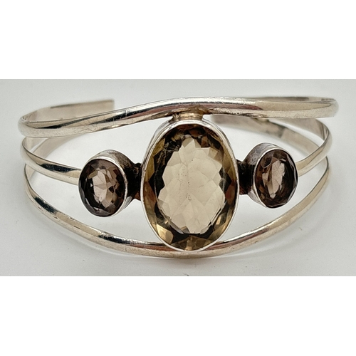 1105 - A modern design silver cuff bangle with central large oval checkerboard cut smoked quartz. Flanked b... 