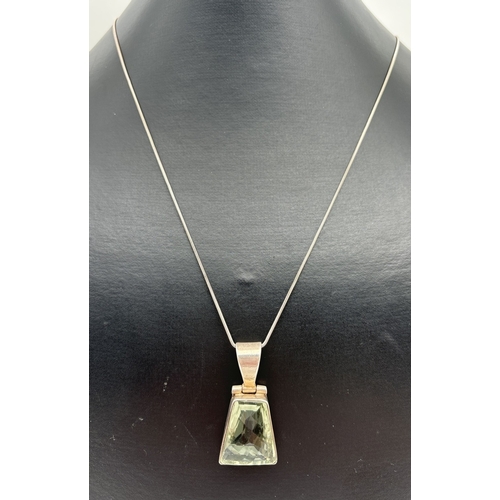 1107 - A silver & green amethyst pendant necklace. Pendant set with a trapeze cut pale green amethyst in a ... 