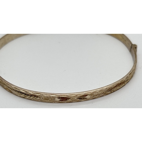 1108 - 3 silver thin band bangles, one hinged with half floral engraved decoration and with safety chain. W... 