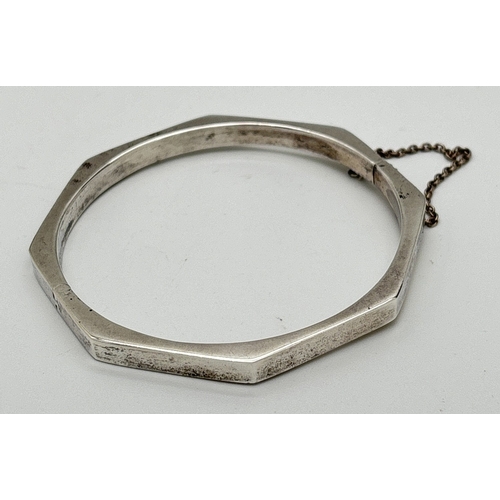 1121 - A silver Octagonal shaped hinged bracelet with safety chain and clip clasp. Stamped 925 on clasp. Sa... 