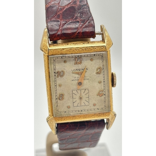 A vintage Longines wristwatch with square shaped 10k gold filled case, possibly 1940's. Pale silver face with gold hour markers and secondary dial. Only one gold hand. Engraved floral decoration to edges of the case. Back of case marked '10k Gold Filled'. Winds but working intermittently. On a replacement leather strap.