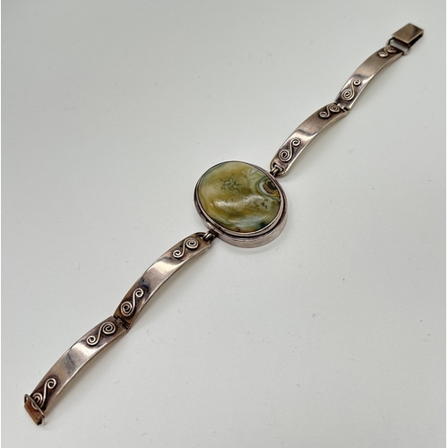 1003 - A modern design silver bracelet with 4 hinged links & a large green agate cabochon. Scroll decoratio... 