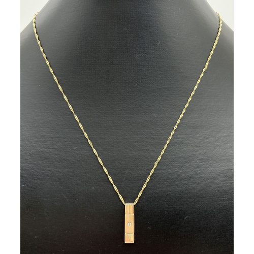 1050 - A 9ct gold modern design drop pendant set with a small round cut diamond, on an 18