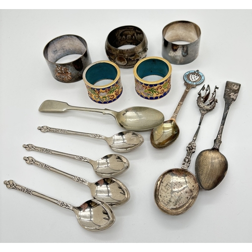 1170 - A small collection of silver and metalware napkin rings and spoons. To include a Georgian silver tea... 