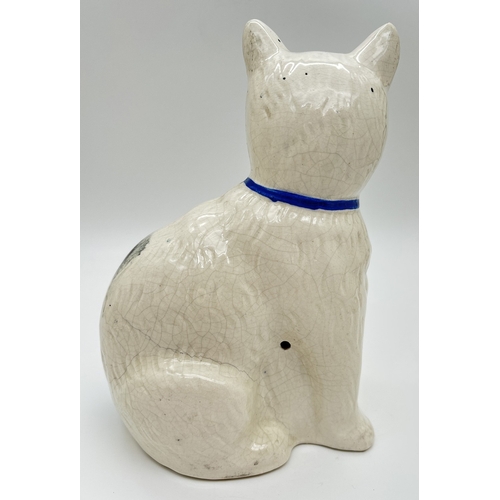 1230 - An antique Staffordshire pottery right facing white and black cat with blue bow to neck. White body ... 