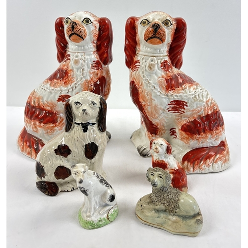 1232 - A collection of Staffordshire and Staffordshire style dog figurines. To include a pair of red and wh... 