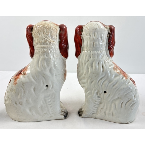 1232 - A collection of Staffordshire and Staffordshire style dog figurines. To include a pair of red and wh... 