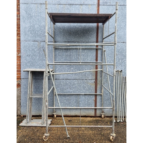 1399 - A galvanised steel scaffold tower with wheels and platform boards. 1.3 x 1.3m square. Minimum platfo... 