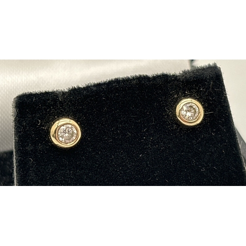 1035 - A pair of 9ct gold diamond stud earrings in a bezel set design. Diamonds total 0.20ct - each earring... 