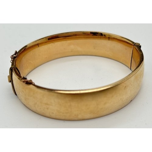 1061 - A vintage 1/5th 9ct gold metal core bangle with half engraved detail of scroll & foliate design. Pus... 