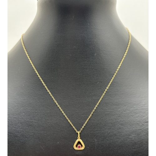 1062 - A 9ct gold triangular pendant set with a small round cut ruby, on a 16 inch fine belcher chain with ... 