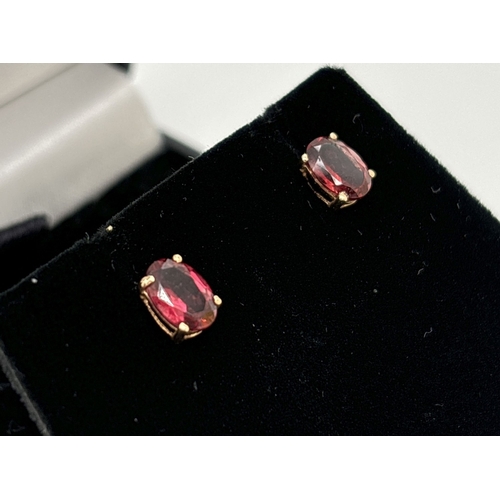 1083 - A pair of 14ct gold garnet stud earrings. Each earring set with an oval cut garnet. Gold marks on bu... 