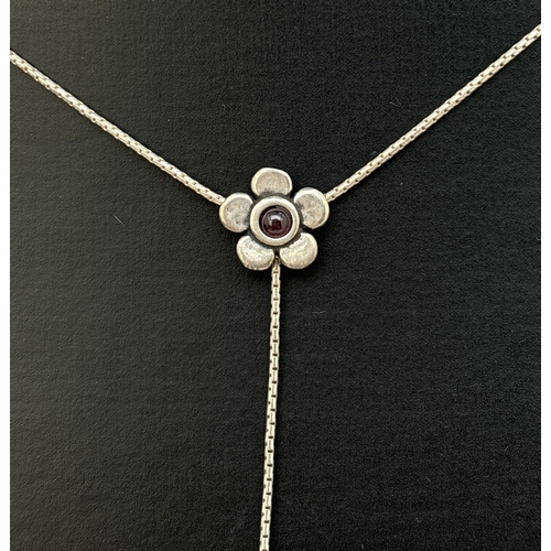 1111 - A silver and garnet set floral design necklace and matching drop style earrings. A 16