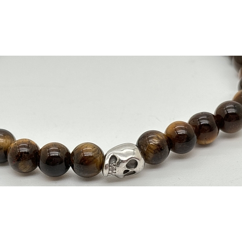 1117 - A tigers eye beaded expanding men's bracelet with silver tone skull bead. By Simon Carter, London.