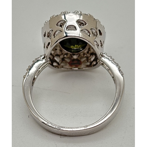 1120 - A rhodium plated costume jewellery cocktail ring set with Swarovski crystals. Large oval cut green s... 