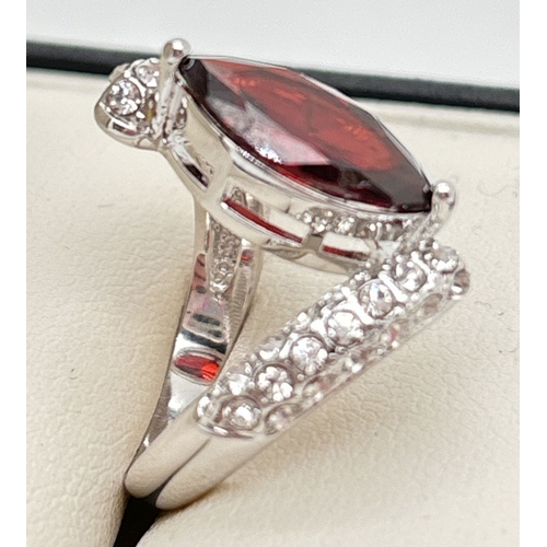 1123 - A rhodium plated twist design cocktail ring set with Swarovski crystals. Central marquise cut red st... 