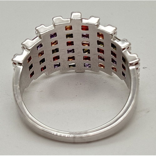 1124 - A rhodium plated band style cocktail ring set with alternating rows of clear and multi coloured Swar... 