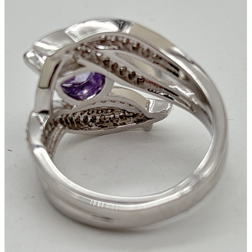 1126 - A rhodium plated cocktail ring in a crossover design set with small round clear and a single marquis... 