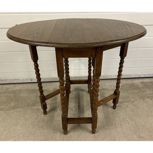 1414 - A small vintage dark oak barley twist drop leaf occasional table with gate leg supports and oval sha... 