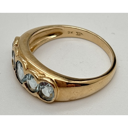 7 - A 9ct gold dress ring with 5 oval cut bezel set blue topaz stones. Central stone approx. 6 x 4mm wit... 